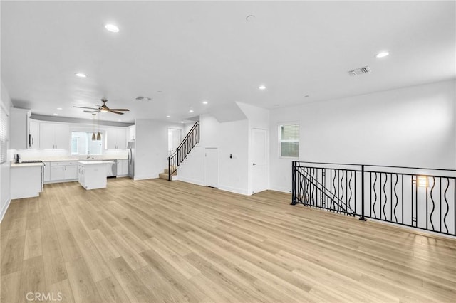 unfurnished living room with sink, light hardwood / wood-style flooring, and ceiling fan