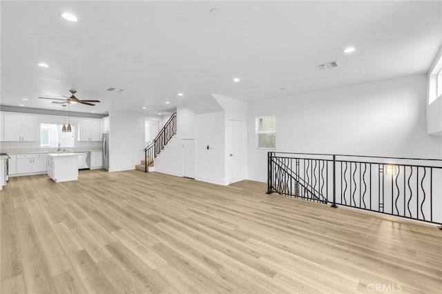 unfurnished living room with ceiling fan, plenty of natural light, and light wood-type flooring