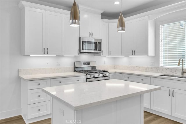 kitchen with sink, decorative light fixtures, a center island, appliances with stainless steel finishes, and white cabinets