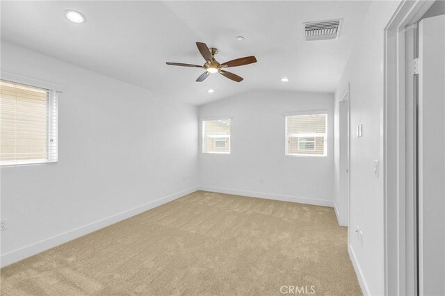 unfurnished room featuring vaulted ceiling, a wealth of natural light, and light colored carpet