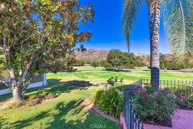 view of yard with view of golf course, fence, and a mountain view