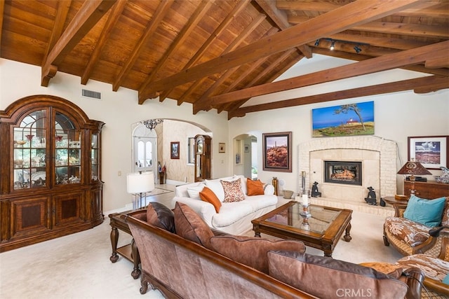 living room with visible vents, a brick fireplace, beam ceiling, wooden ceiling, and arched walkways