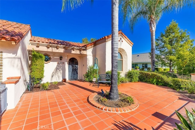 exterior space featuring a tile roof, a patio area, fence, and stucco siding