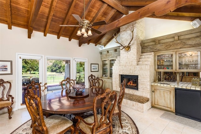 dining area featuring beam ceiling, high vaulted ceiling, a ceiling fan, wet bar, and wood ceiling