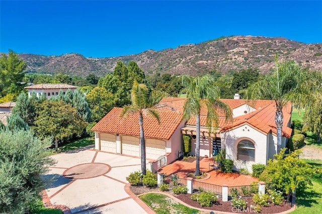 view of front of home with a tile roof, fence, a mountain view, and stucco siding