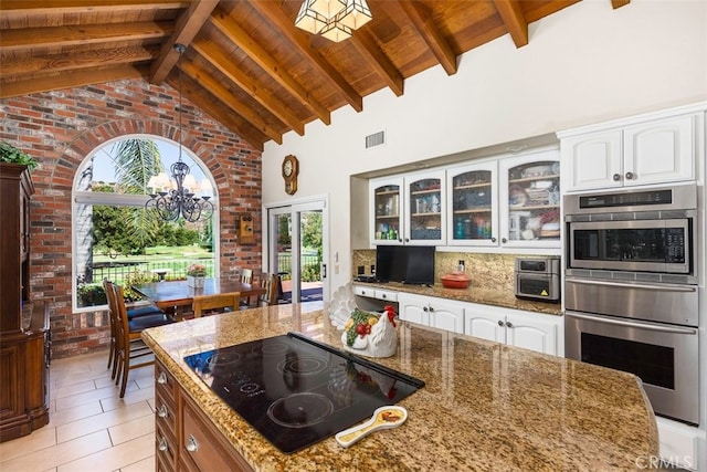 kitchen featuring visible vents, stainless steel double oven, decorative backsplash, glass insert cabinets, and black electric stovetop