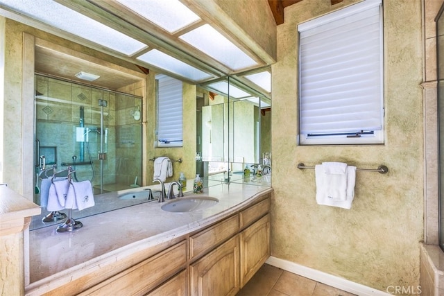 bathroom with tile patterned flooring, vanity, a stall shower, and baseboards