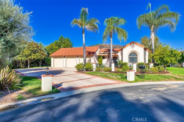 mediterranean / spanish-style home with a garage, a fenced front yard, concrete driveway, and a tiled roof