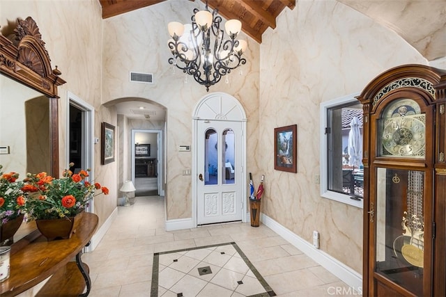 entrance foyer featuring visible vents, baseboards, beamed ceiling, a towering ceiling, and arched walkways