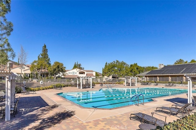 community pool with a patio, a pergola, and fence