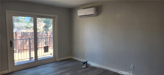 spare room with a wall mounted air conditioner and dark hardwood / wood-style floors