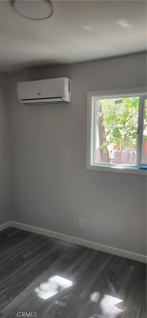 unfurnished room with a wall mounted air conditioner and dark hardwood / wood-style floors