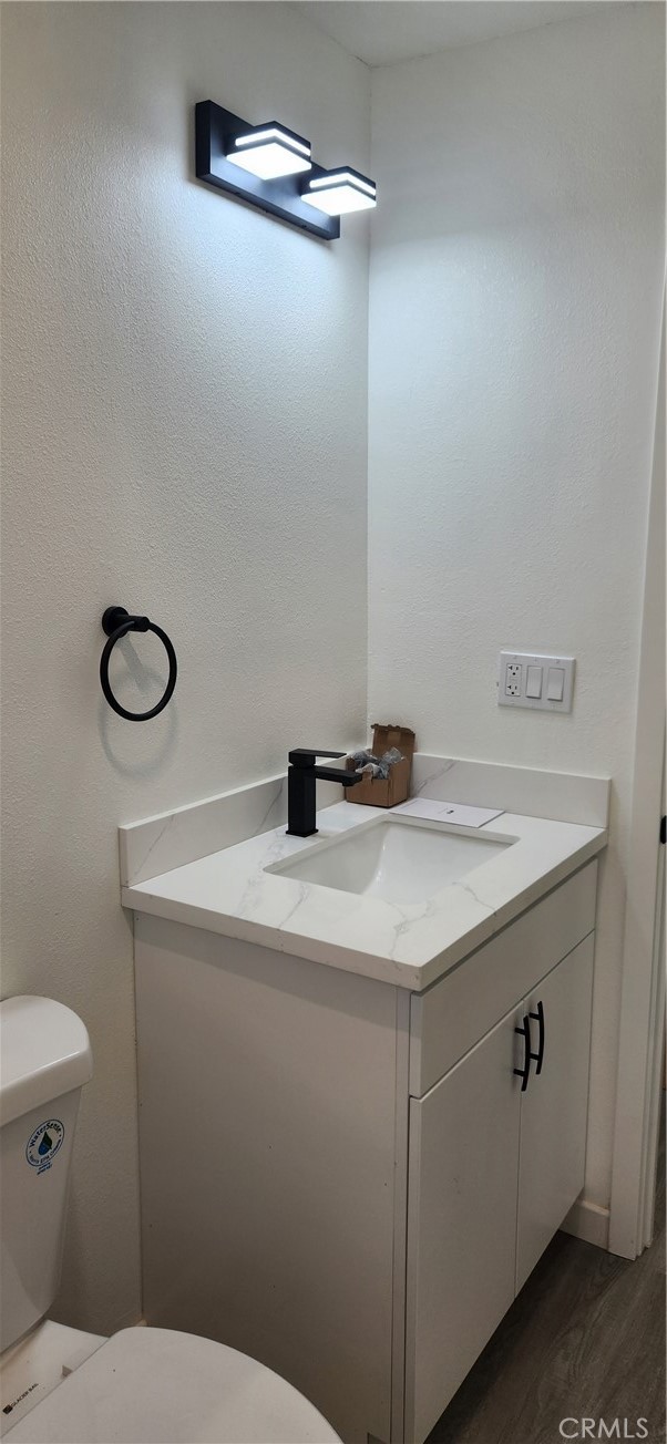 bathroom featuring vanity, hardwood / wood-style flooring, and toilet