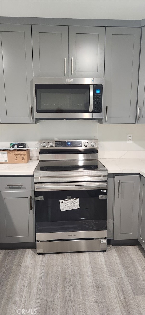 kitchen featuring appliances with stainless steel finishes, gray cabinets, and light wood-type flooring