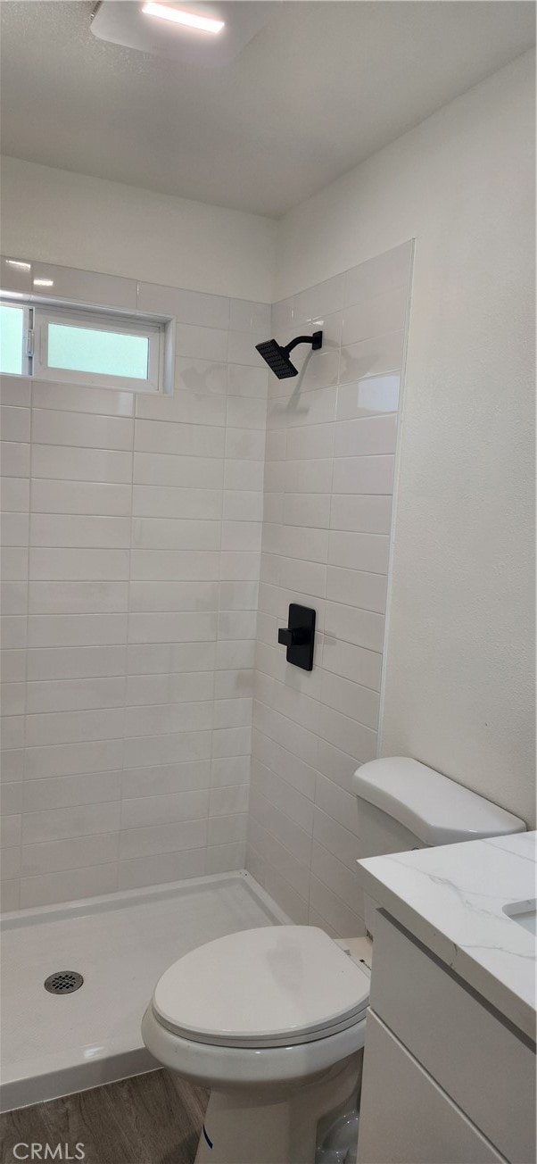 bathroom with vanity, toilet, and tiled shower