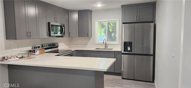 3590 Redwood St, Clearlake, CA 95422 - kitchen featuring stainless steel appliances, gray cabinets, a peninsula, light wood-style flooring, and light stone countertops