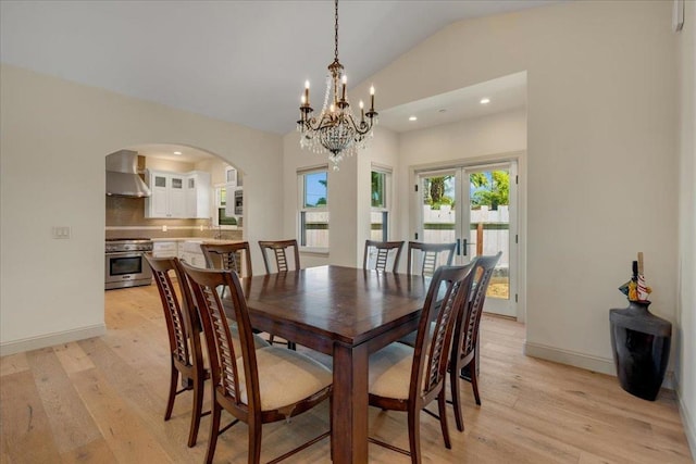 dining space featuring french doors, light hardwood / wood-style floors, lofted ceiling, and an inviting chandelier