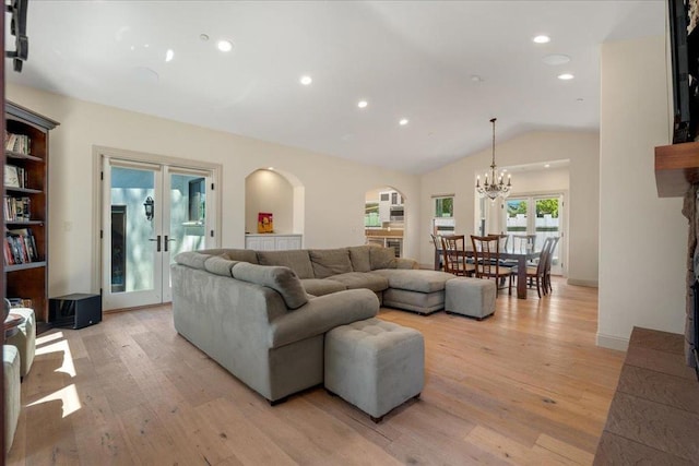 living room with french doors, light hardwood / wood-style flooring, a notable chandelier, and vaulted ceiling