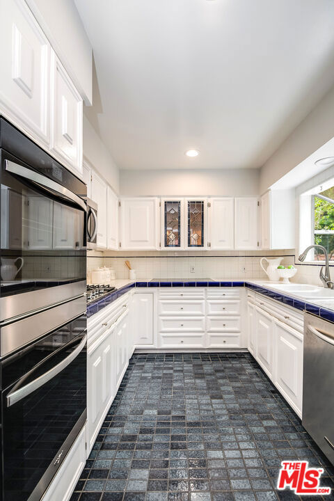 kitchen with white cabinets, appliances with stainless steel finishes, tasteful backsplash, and sink