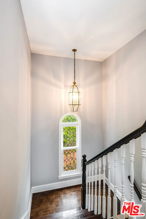 stairway featuring hardwood / wood-style floors and a notable chandelier