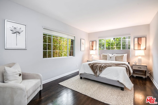 bedroom with multiple windows and dark hardwood / wood-style floors