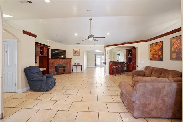 living room featuring crown molding, a fireplace, light tile patterned flooring, and ceiling fan