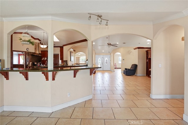 kitchen with a kitchen breakfast bar, ornamental molding, ceiling fan, and tasteful backsplash