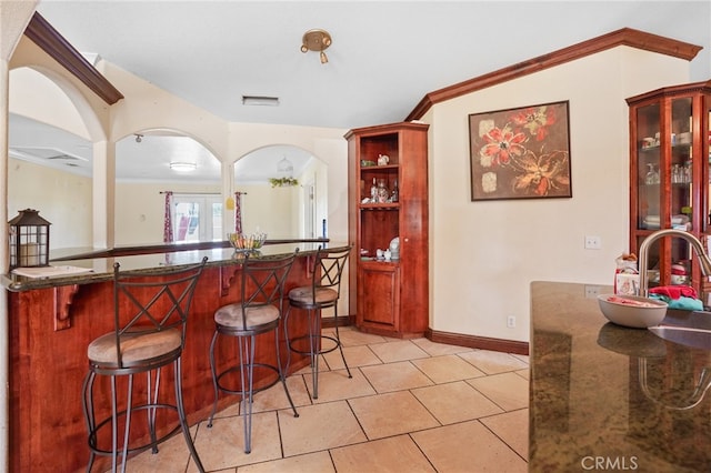 bar with ornamental molding, light tile patterned floors, and sink