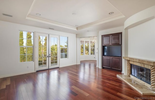 unfurnished living room with french doors, a tray ceiling, and dark hardwood / wood-style flooring