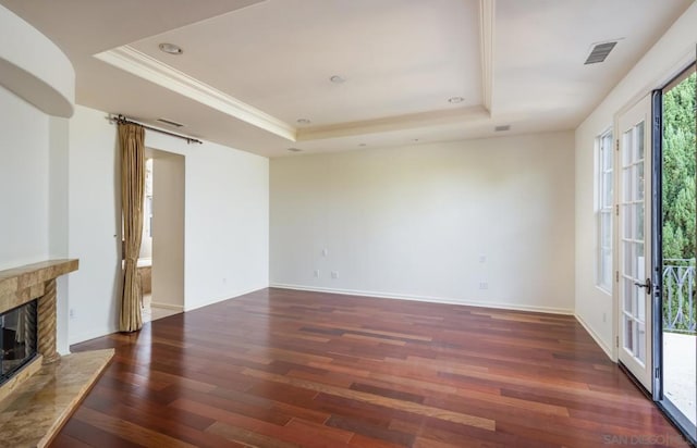 unfurnished living room with a stone fireplace, a raised ceiling, and dark hardwood / wood-style flooring