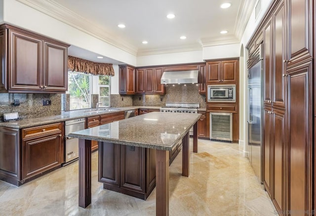 kitchen featuring built in appliances, a kitchen island, a kitchen breakfast bar, extractor fan, and stone countertops