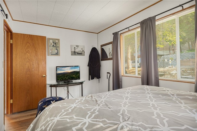 bedroom featuring multiple windows, crown molding, and hardwood / wood-style floors