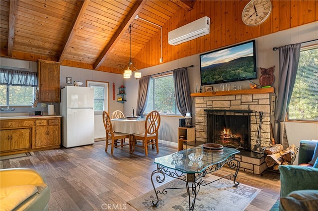 living room featuring a healthy amount of sunlight, wood-type flooring, a stone fireplace, and a wall mounted AC