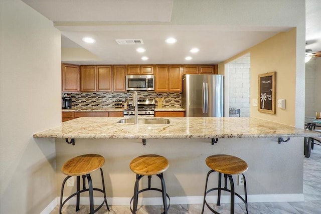 kitchen featuring decorative backsplash, appliances with stainless steel finishes, and a breakfast bar area