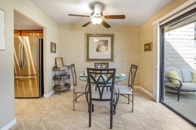 dining room featuring ceiling fan and brick wall