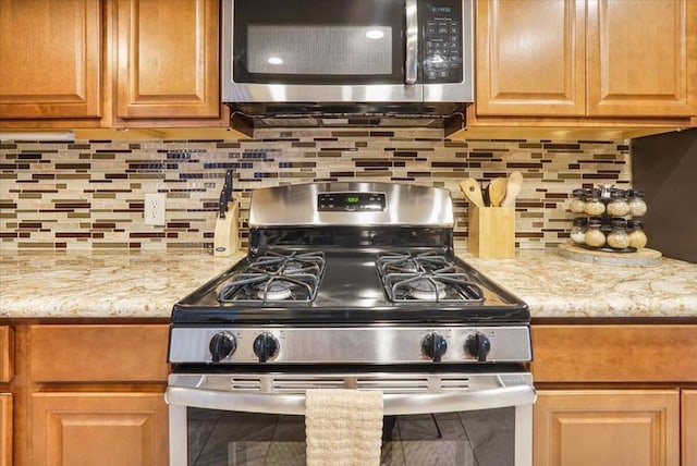 kitchen with backsplash, light stone countertops, and stainless steel appliances