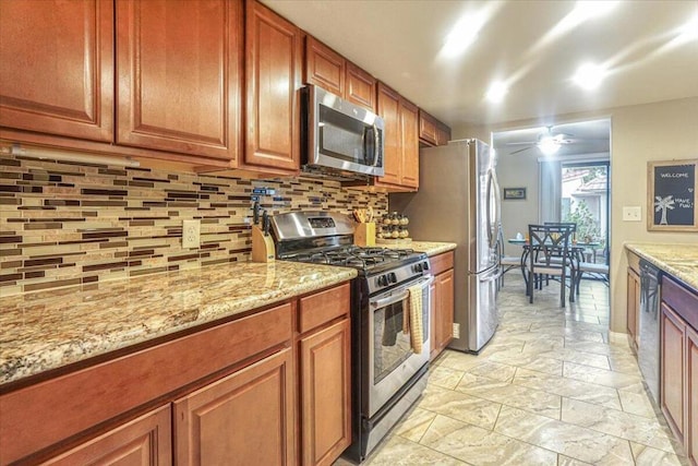 kitchen featuring ceiling fan, stainless steel appliances, tasteful backsplash, and light stone counters