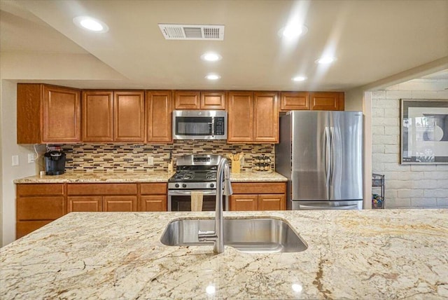 kitchen featuring appliances with stainless steel finishes, sink, and light stone counters