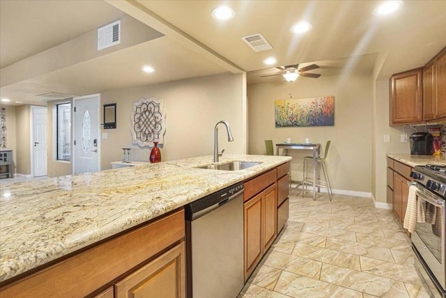 kitchen featuring ceiling fan, sink, light stone counters, and appliances with stainless steel finishes