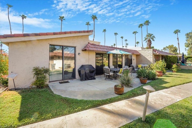 rear view of house featuring a lawn and a patio