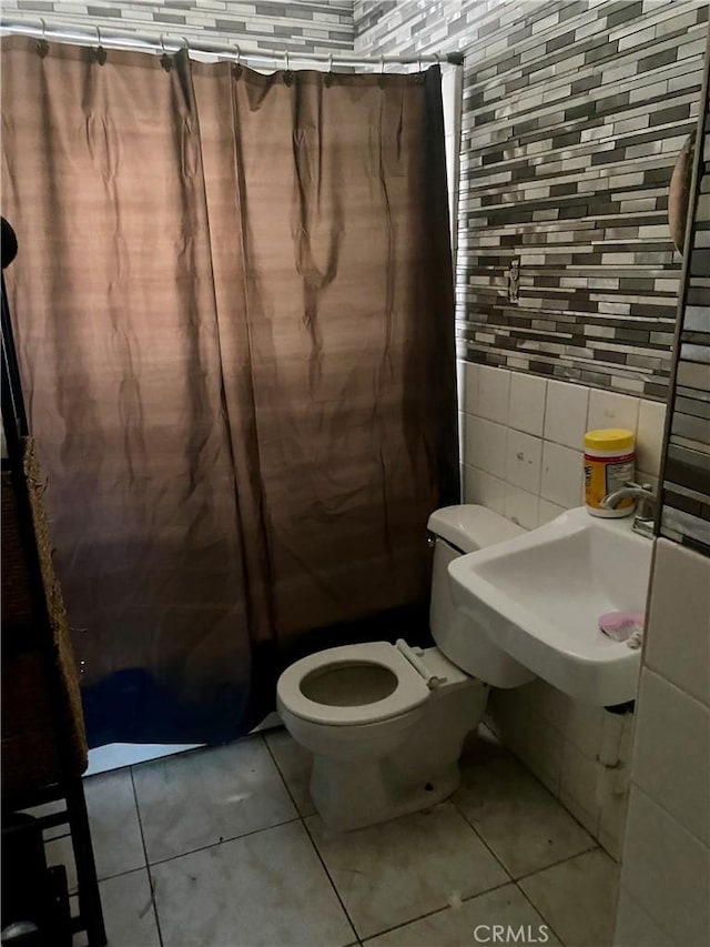 bathroom featuring toilet, tile patterned floors, and tile walls