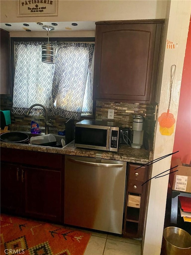 kitchen featuring decorative backsplash, dark brown cabinets, stainless steel appliances, sink, and light tile patterned floors