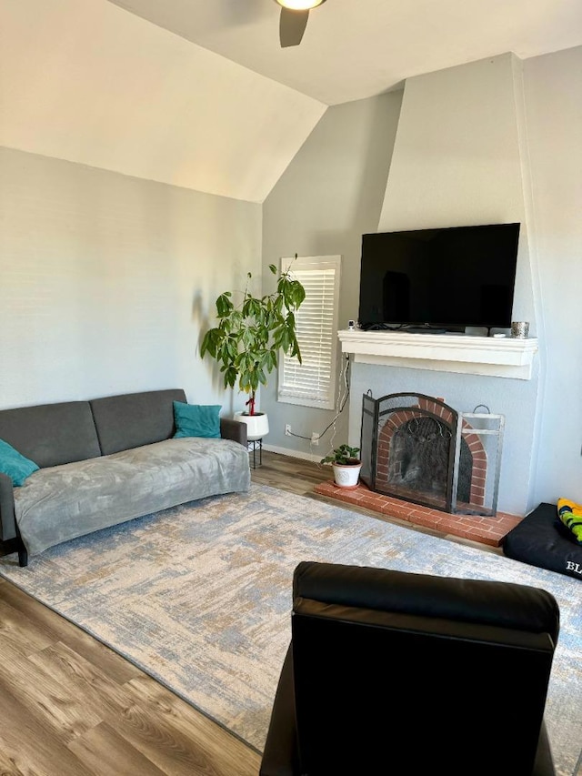 living room with a brick fireplace, hardwood / wood-style flooring, lofted ceiling, and ceiling fan