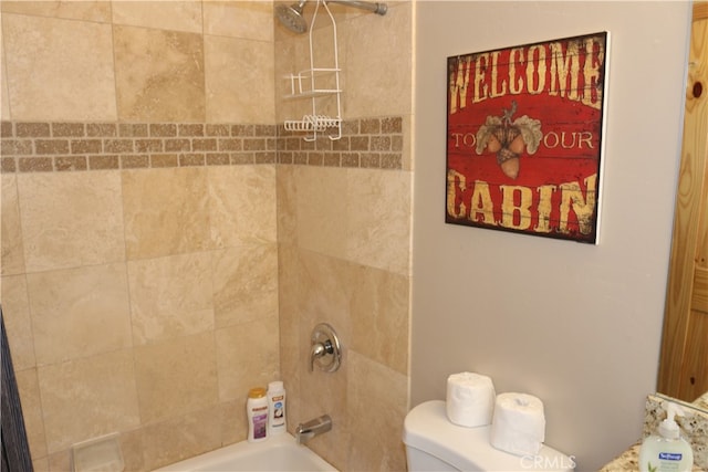 bathroom featuring tiled shower / bath combo and toilet