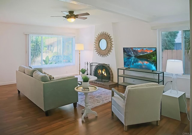 living room featuring a wealth of natural light, ceiling fan, dark wood-type flooring, and a brick fireplace