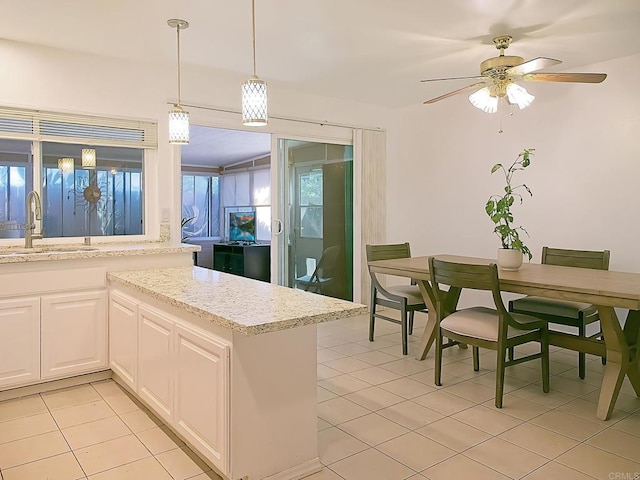 kitchen with light stone countertops, white cabinetry, ceiling fan, and sink