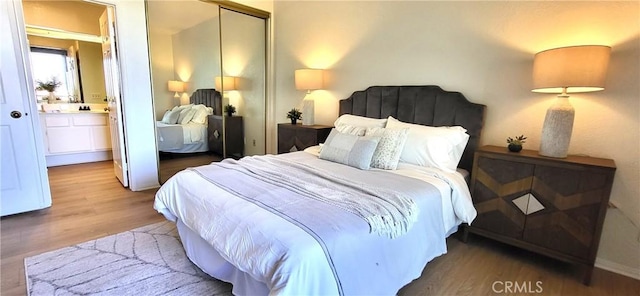 bedroom with ensuite bath, a closet, and hardwood / wood-style flooring