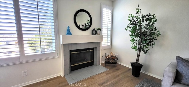 living room featuring a tile fireplace, a wealth of natural light, and hardwood / wood-style flooring