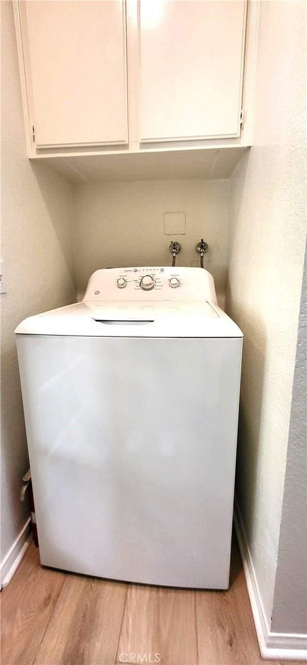 washroom with cabinets, light wood-type flooring, and washer / clothes dryer