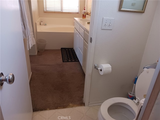 bathroom featuring vanity, a relaxing tiled tub, and toilet